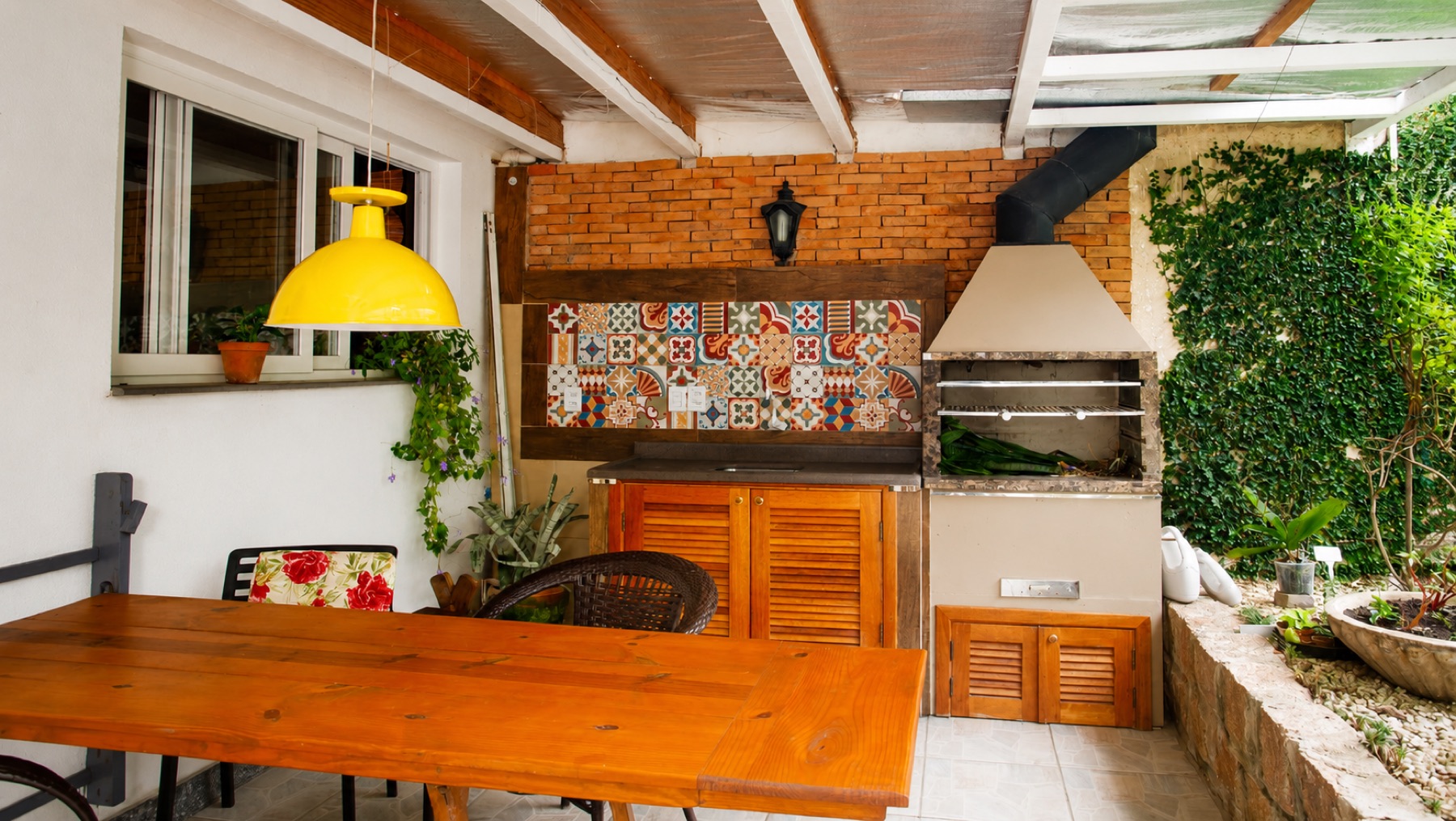 Churrasqueira coberta com mesa, pia e espaço para geladeira externa
